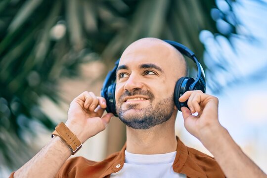 Young hispanic bald man smiling happy using headphones at the city
