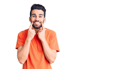 Young handsome man with beard wearing casual t-shirt smiling with open mouth, fingers pointing and forcing cheerful smile