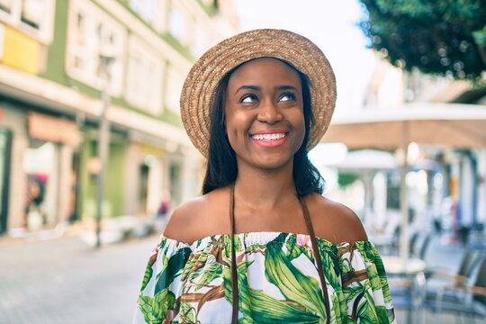 Young african american tourist woman on vacation smiling happy using vintage camera at the city.