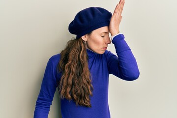 Naklejka premium Young blonde woman wearing french look with beret surprised with hand on head for mistake, remember error. forgot, bad memory concept.