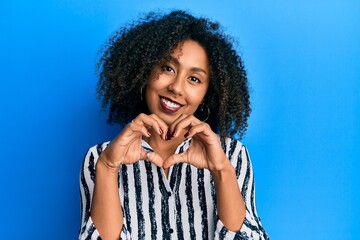 Fototapeta na wymiar Beautiful african american woman with afro hair wearing casual clothes smiling in love doing heart symbol shape with hands. romantic concept.
