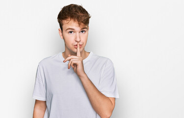 Young caucasian man wearing casual white t shirt asking to be quiet with finger on lips. silence and secret concept.