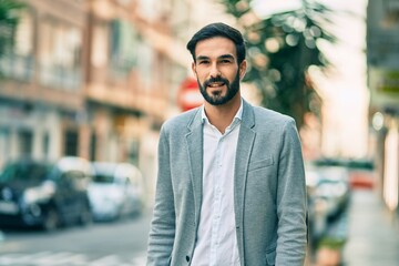 Young hispanic businessman smiling happy standing at the city.