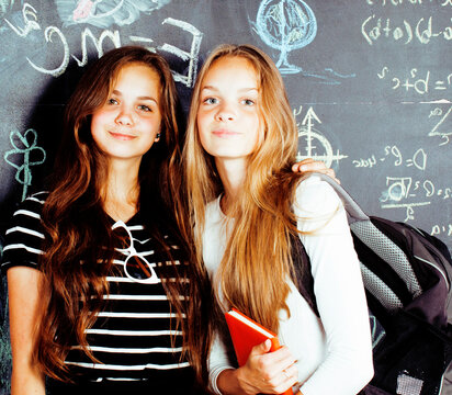 back to school after summer vacations, two teen real girls in classroom with blackboard painted together, lifestyle real people concept