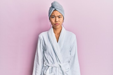 Young chinese woman wearing shower towel cap and bathrobe depressed and worry for distress, crying angry and afraid. sad expression.