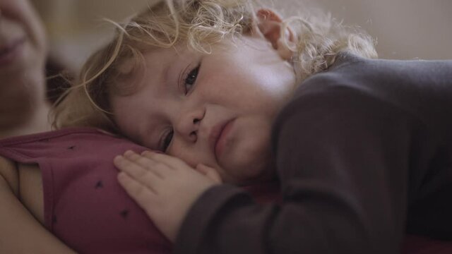 a disgruntled child lies on his mother's chest