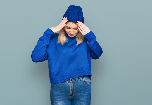Young caucasian woman wearing wool winter sweater and cap suffering from headache desperate and stressed because pain and migraine. hands on head.