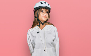 Teenager caucasian girl wearing bike helmet smiling looking to the side and staring away thinking.