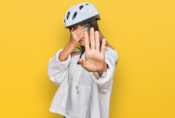 Teenager caucasian girl wearing bike helmet covering eyes with hands and doing stop gesture with sad and fear expression. embarrassed and negative concept.