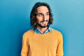 Young hispanic man wearing casual clothes looking to side, relax profile pose with natural face and confident smile.