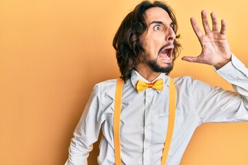 Young hispanic man wearing hipster elegant look shouting and screaming loud to side with hand on mouth. communication concept.