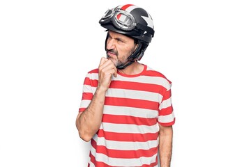 Middle age handsome motorcyclist man wearing moto helmet over isolated white background thinking concentrated about doubt with finger on chin and looking up wondering