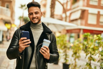 Young arab man using smartphone and drinking coffee at the city.