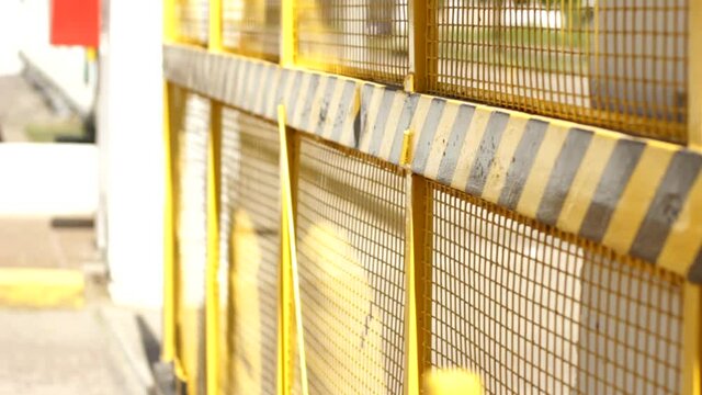 Yellow and black large factory gate opens outdoors. Industry to street during sunny day.