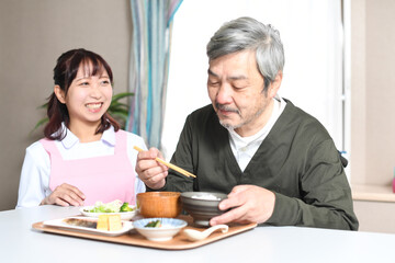 食事をする高齢者男性とエプロン姿の女性介護士