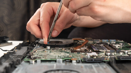 laptop maintenance, the master of the service center unscrews the motherboard with a screwdriver.