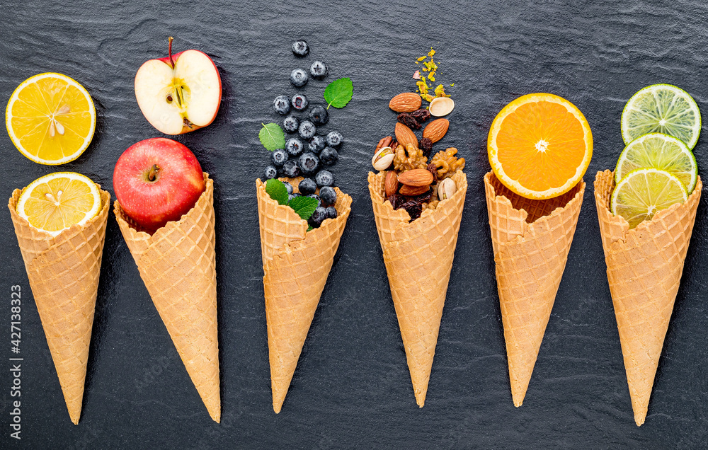 Poster various of ingredient for ice cream flavor in cones set up on dark stone background .