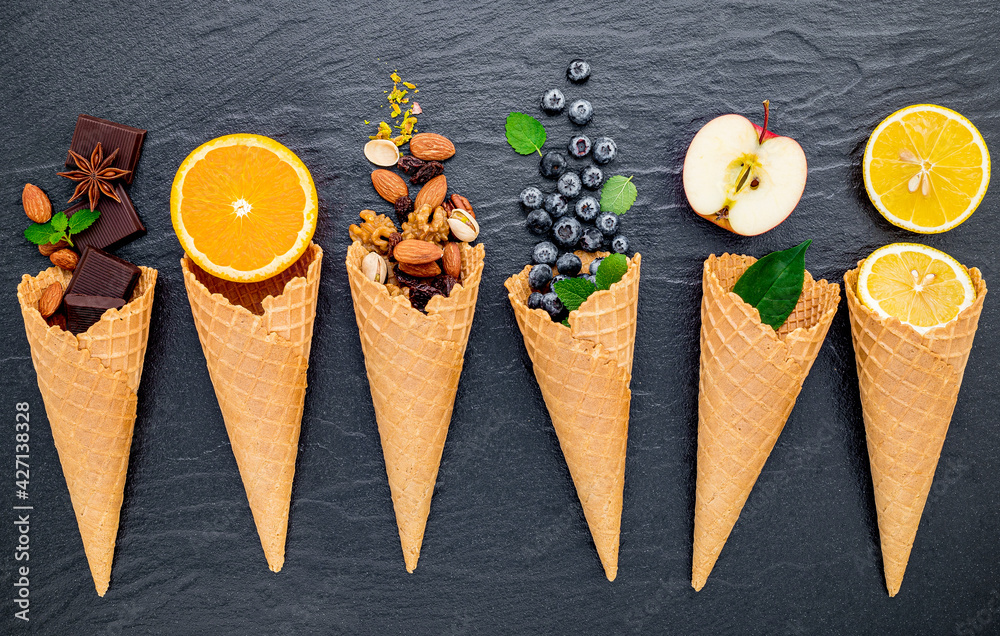 Poster various of ingredient for ice cream flavor in cones set up on dark stone background .