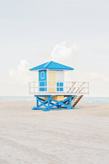 Beautiful light airy tropical Florida landscape with blue yellow lifeguard house. American Florida beach ocean view with lifeguard tower, water, sand and sky. Empty beach at sunset or sunrise outdoor