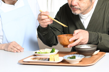 食事をする高齢者男性とエプロン姿の男性介護士