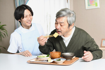 食事をする高齢者男性とエプロン姿の女性介護士 Wall Mural こうまる 食事をする高齢者男性とエプロン姿の女性介護士 Wall Mural こうまる
