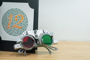 Optical equipment, optical trial lens frame on wooden table, and color blindness test chart in...