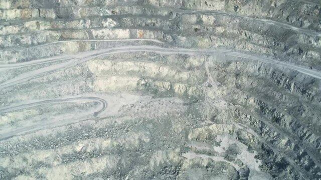 Aerial view of Huge asbestos quarry. Inside the quarry there is a serpentine road for trucks. In the center of the frame is a site loaded with explosives.
