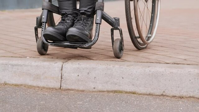 A person with a disability moves along the street in a wheelchair