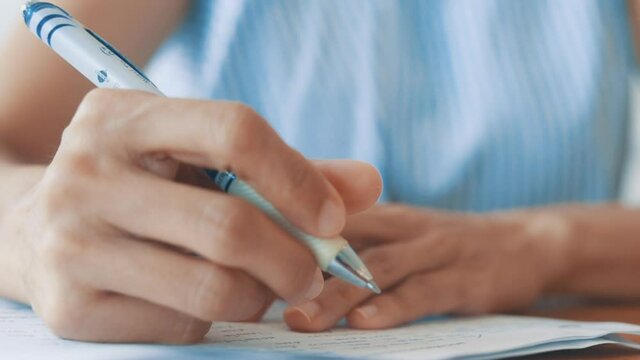 HD Close up hand of business women use pen writing document paper. Female hand close up writing with a blue pen on a white sheet. Woman writes information on a piece of paper.