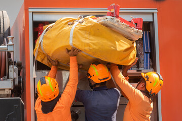 Firemen preparing a yellow bag containing a fire escape device that use as vertical escape chute...