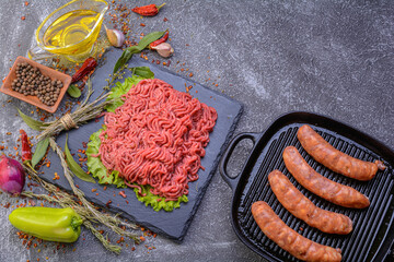 Fresh minced pork and sausage in a natural shell, decorated with garlic, red pepper and dill on a slate stone.Dark texture background.Flat layout.top view.culinary background.