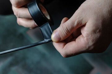 A man is insulating a black electrical wire.