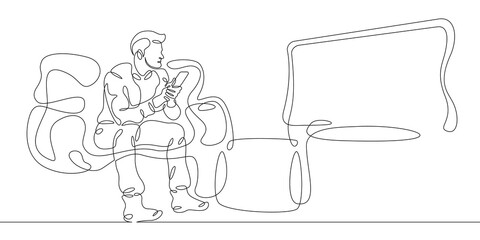 Young man watching television at home on the couch.