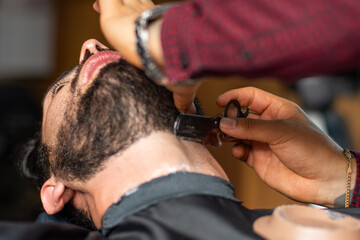 Barber shaving client's beard with a razor