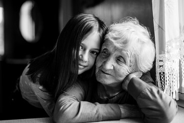 Little girl hugs her old grandmother. Black and white photo.