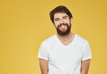 Fototapeta premium portrait of a man in a white t-shirt on a yellow background cropped view Copy Space