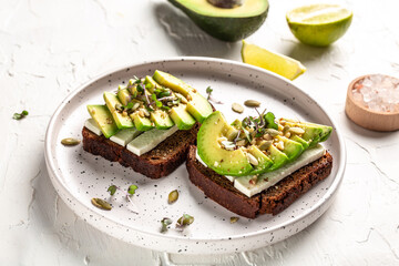 Healthy avocado toasts with rye bread, sliced avocado, cheese, pumpkin, nut and sesame for breakfast or lunch. Vegetarian food. Vegan menu. Food recipe background. Close up