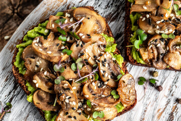 avocado, mushrooms and microgreen whole grain sandwich. Decorated with sesame. Vegetarian food. Vegan menu. Food recipe background. Close up