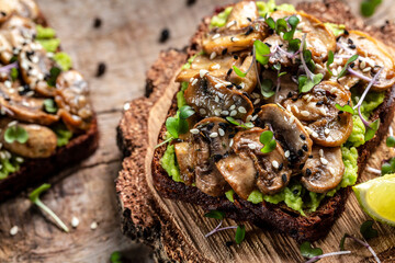 avocado, mushrooms and microgreen whole grain sandwich. Decorated with sesame. Vegetarian food. Vegan menu. Food recipe background. Close up