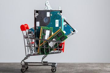 A concept image with a small shopping cart filled with computer parts including RAM memory cards...