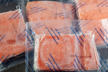 Closeup isolated image of four packs of individually packaged salmon fillets. The air tight vacuum...