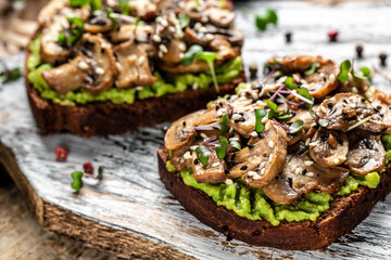 Toast avocado, mushrooms and microgreen whole grain sandwich. Decorated with sesame. Vegetarian food. Vegan menu. Food recipe background