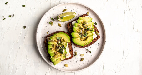Healthy avocado toasts for breakfast or lunch with rye bread, sliced avocado, cheese, pumpkin and sesame seeds. banner, catering menu recipe top view