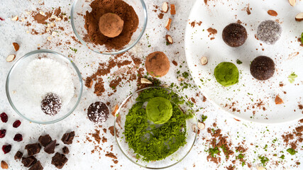 Fototapeta na wymiar Super food energy balls. No bake homemade raw vegetarian fitness dessert covered by matcha tea powder, coconut powder and cocoa powder. Healthy eating. Candy making process. Selective focus. Top view.