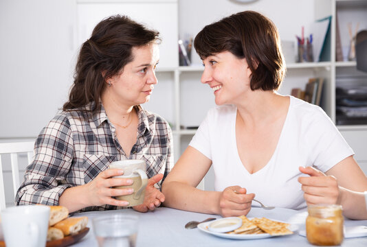 Two woman friends talking and drinking tea in the kitchen. High quality photo