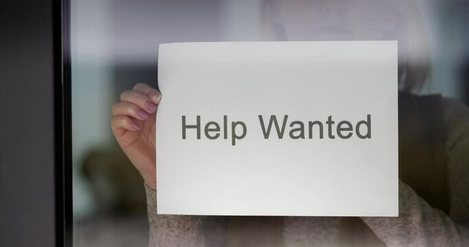Employee hangs on the door ad Help Wanted