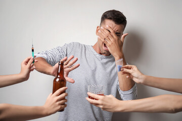 Male junkie refusing to take drugs and alcohol near light wall