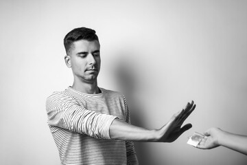 Male junkie refusing to take drugs near light wall