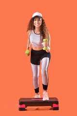 Beautiful young woman training with dumbbells on color background