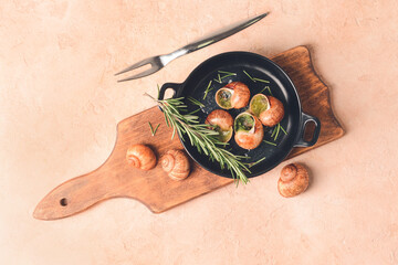Frying pan with tasty snails on color background